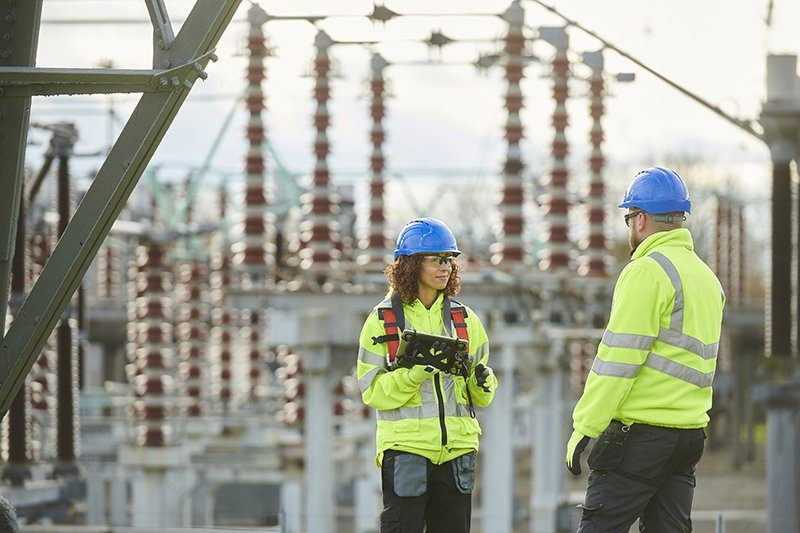 Field crews in high-visibility gear at a substation